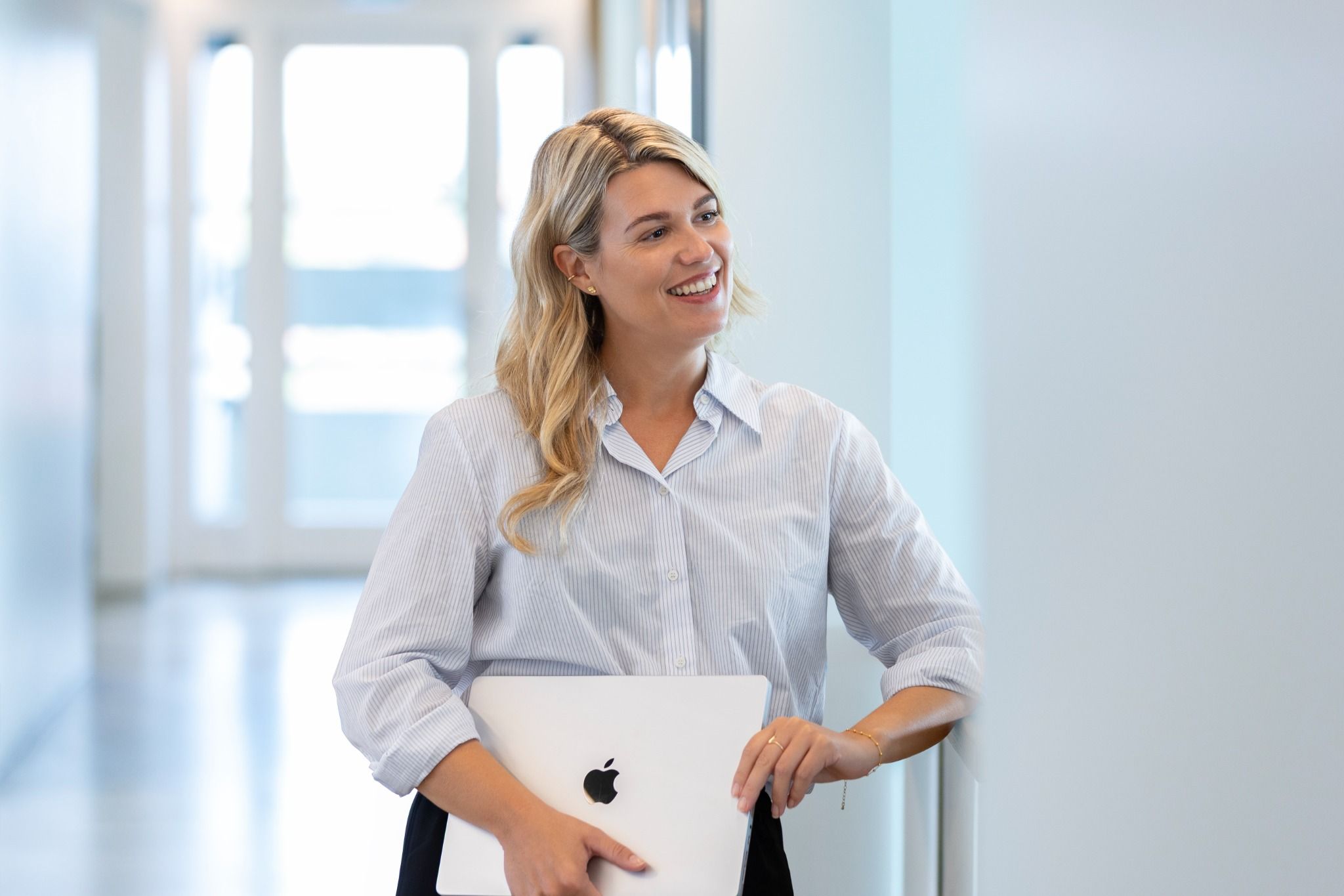 Smilende medarbejder i gang med bærbar computer i lys kontorgang