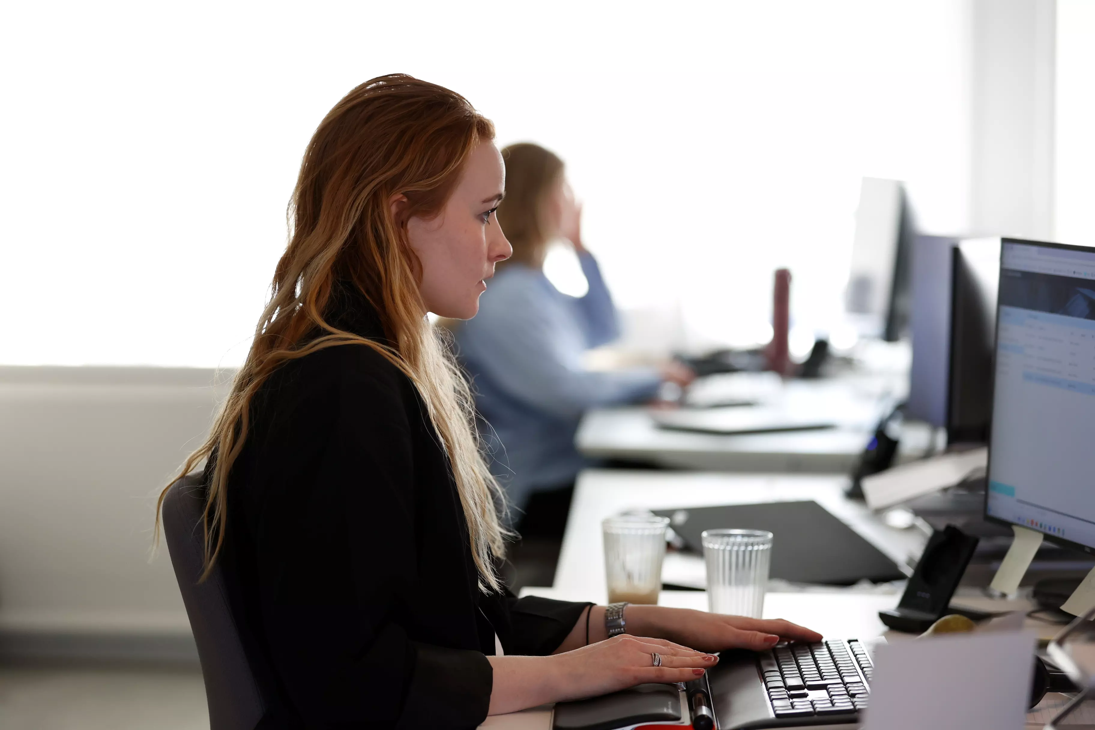 En kvinde ses fra siden mens hun arbejder ved en computer.