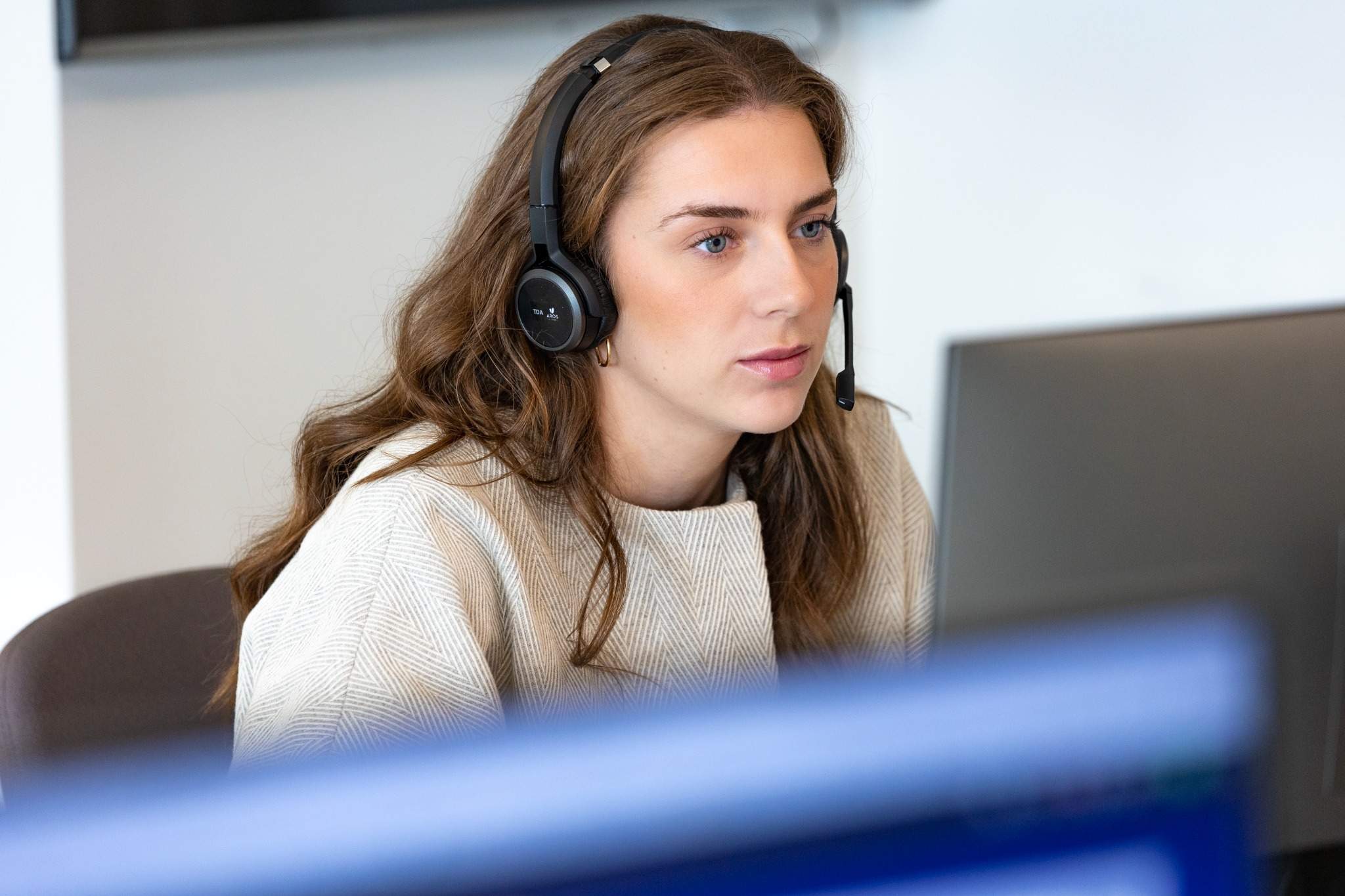 Medarbejder med headset ser koncentreret på skærm i kontormiljø