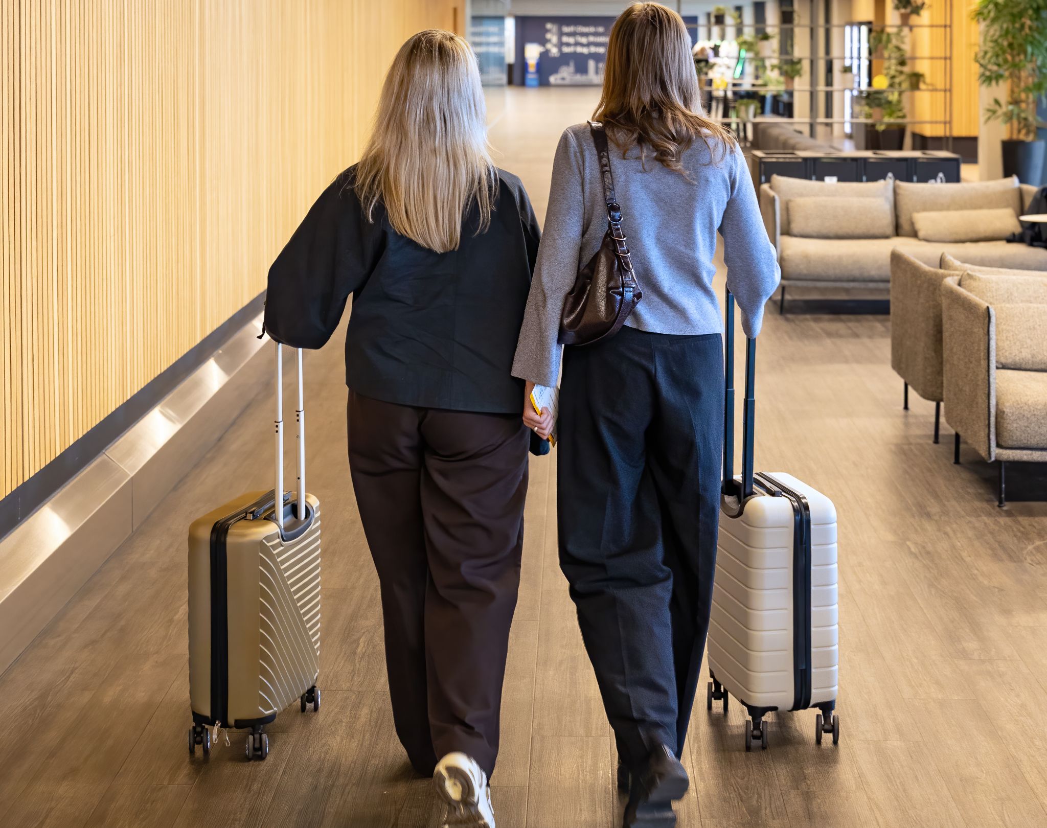 To kvinder går i lufthavnen med kufferter