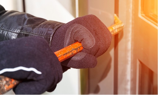 Hænder med handsker på, der forsøger at brække en dør op. 