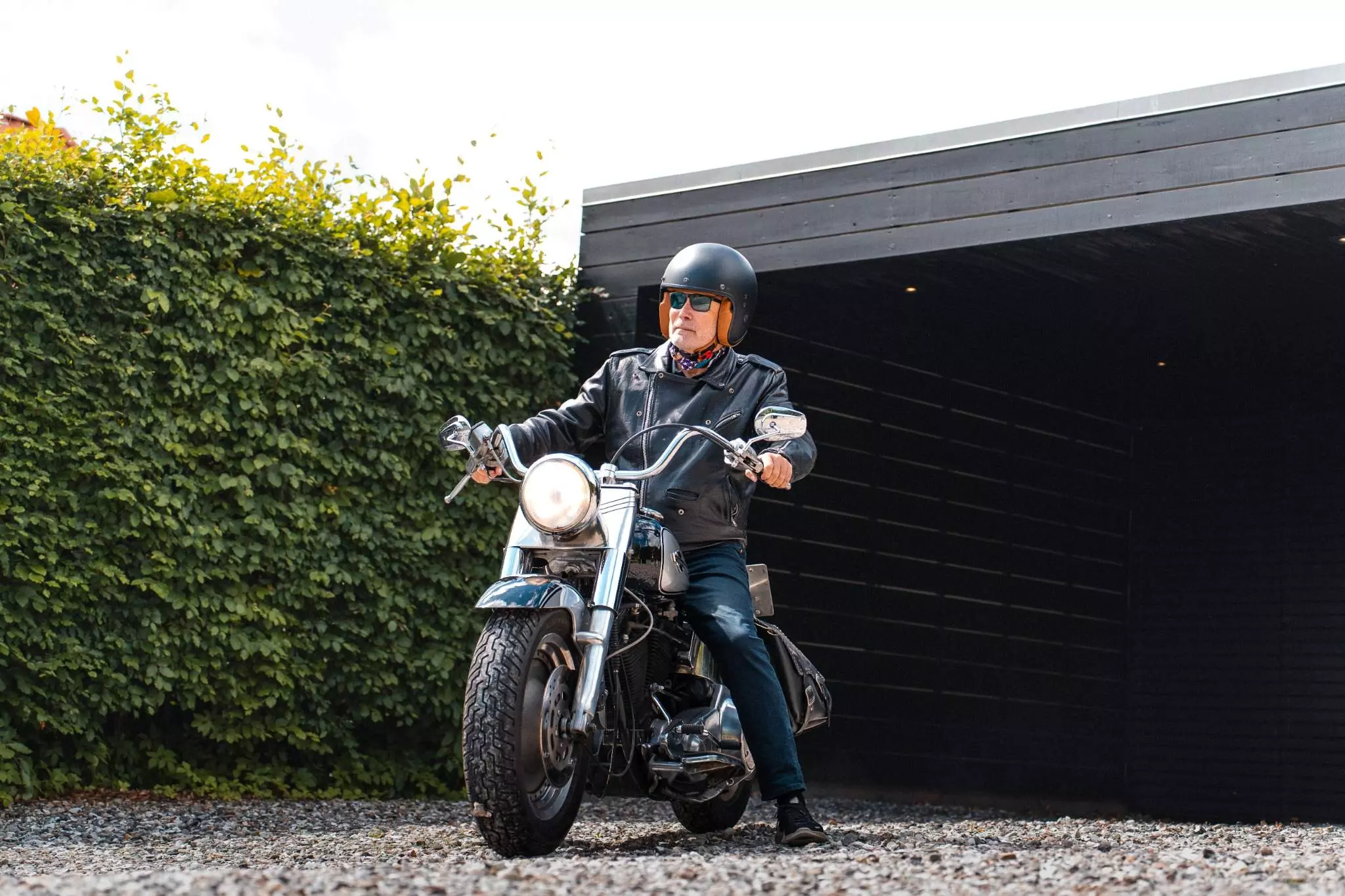 Mand sidder på veteranmotorcykel Harley Davidson i indkørsel