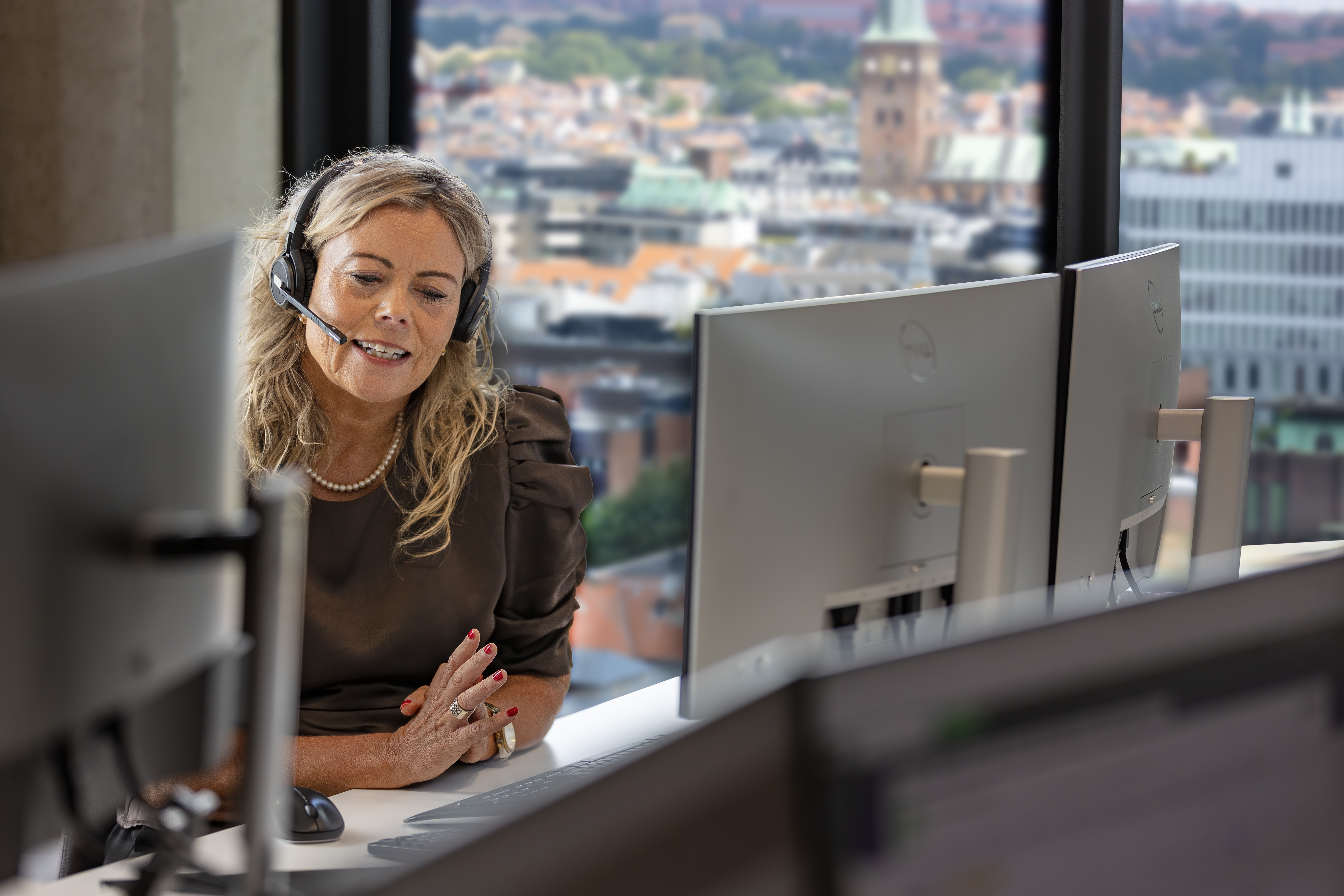 Kundeservicemedarbejder snakker i telefon med Aarhus i baggrunden