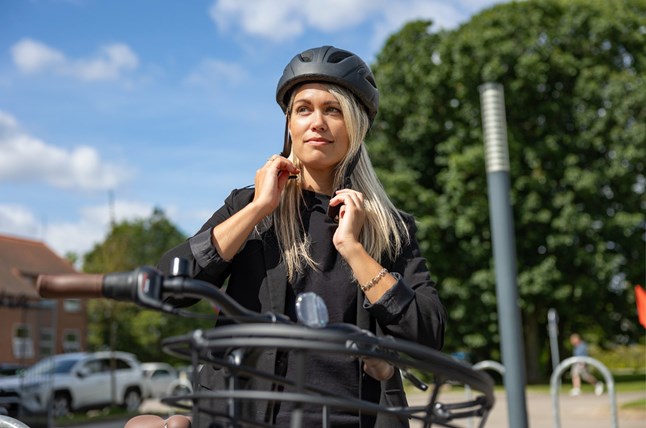 Kvinde spænder cykelhjelm: sikkerhed på cykel med Aros Forsikring.
