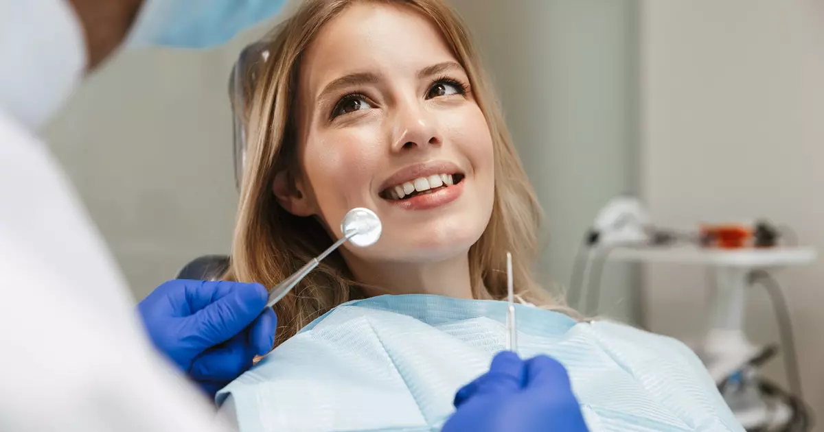 En kvinde er til tandlæge og man ser hende sidde i stolen. Hun smiler og er klar til behandling.