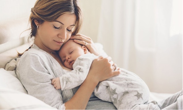 En mod har sit barn på brystet. 