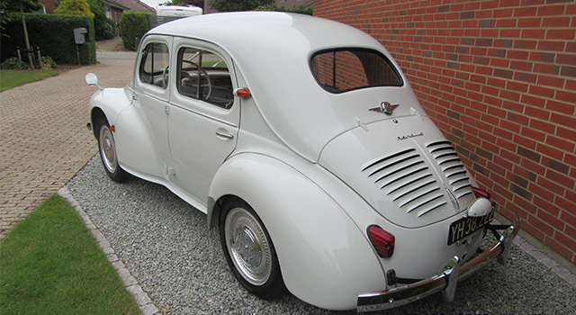 Billedet viser en veteranbil der holder parkeret foran et hus.