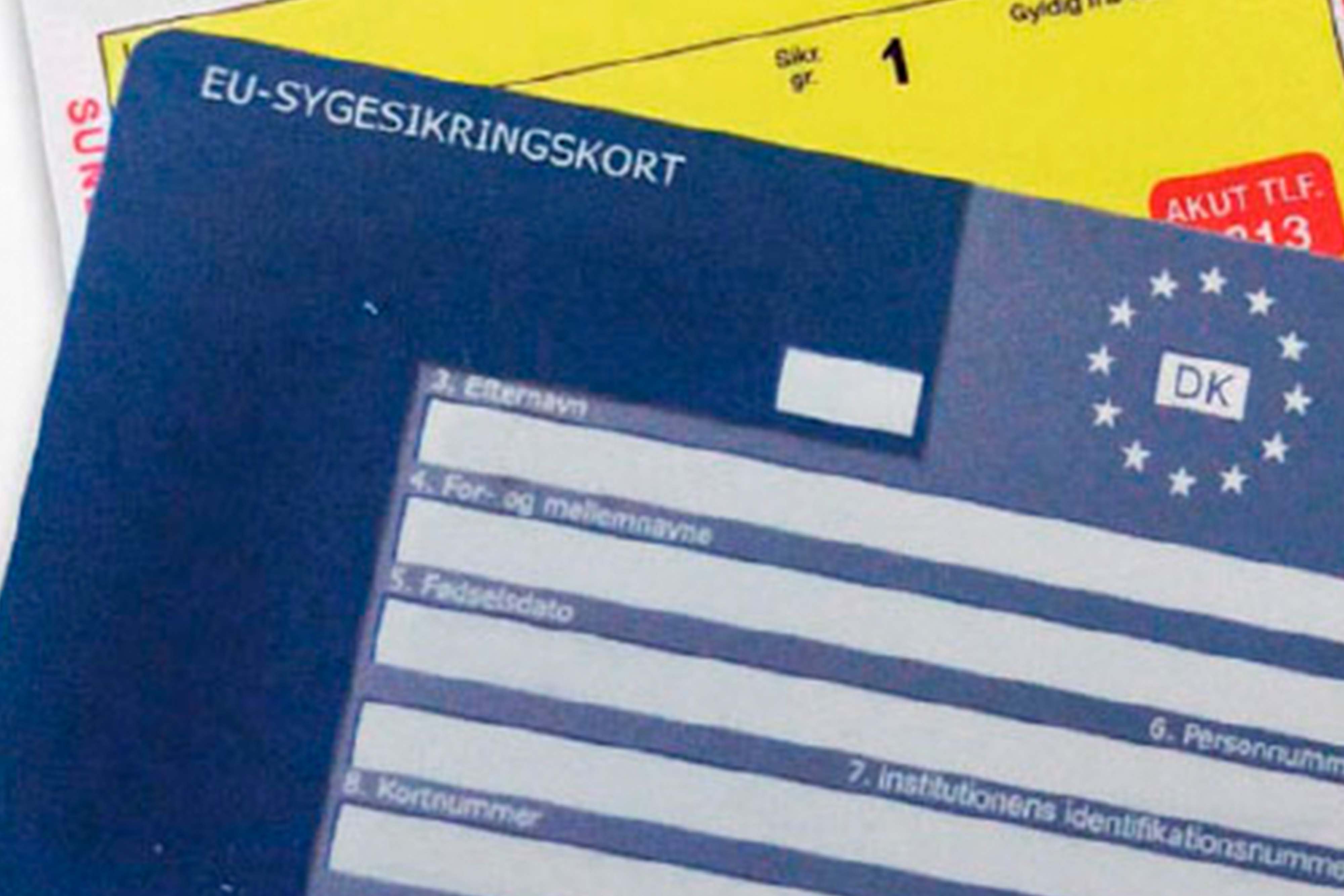 Blå sygesikringsbevis og almindelig sygesikringsbevis i baggrunden.