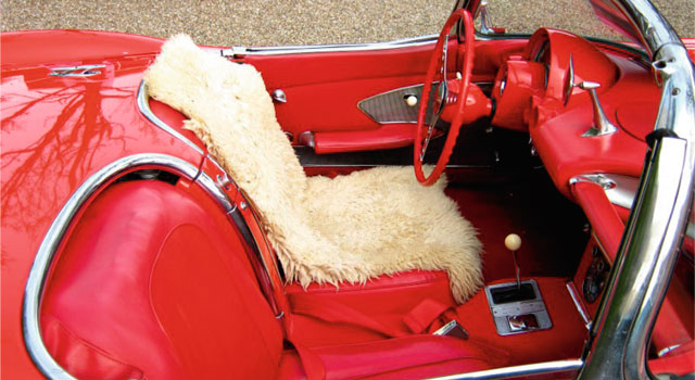 Man ser en åben bil indefra, med rødt interiør. Bilen er højst sandsynlig en veteranbil.