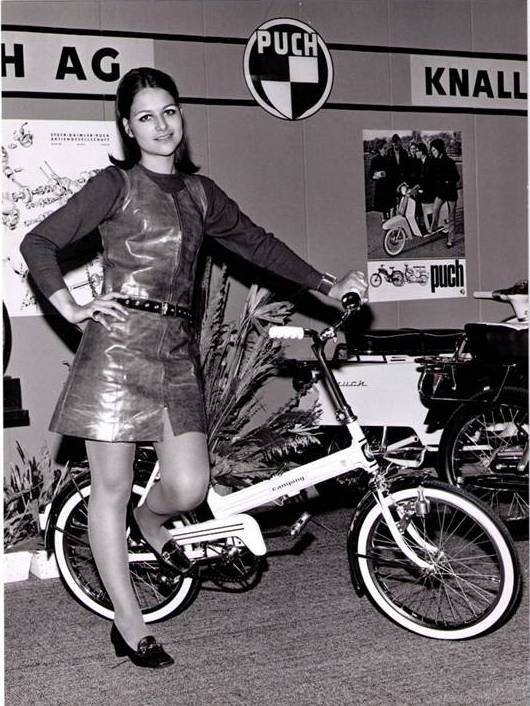 Billedet er et retro billede af en kvinder der står med en puch maxi. Det er i sort/hvid. 