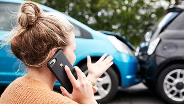 Kvinde taler i telefonen mens hun er vidne til to biler der er stødt sammen.
