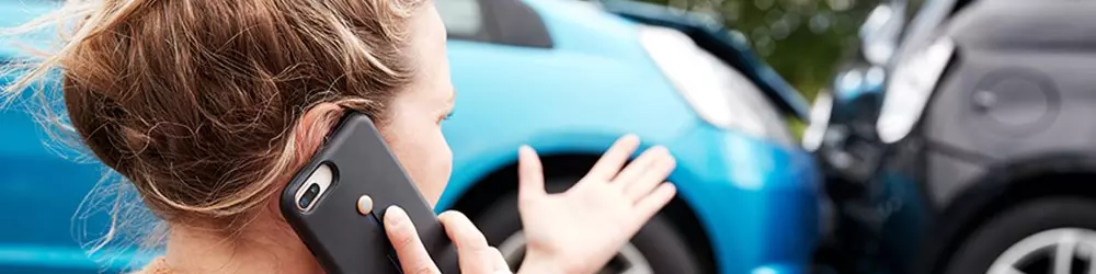 Kvinde taler i telefonen mens hun er vidne til to biler der er stødt sammen.