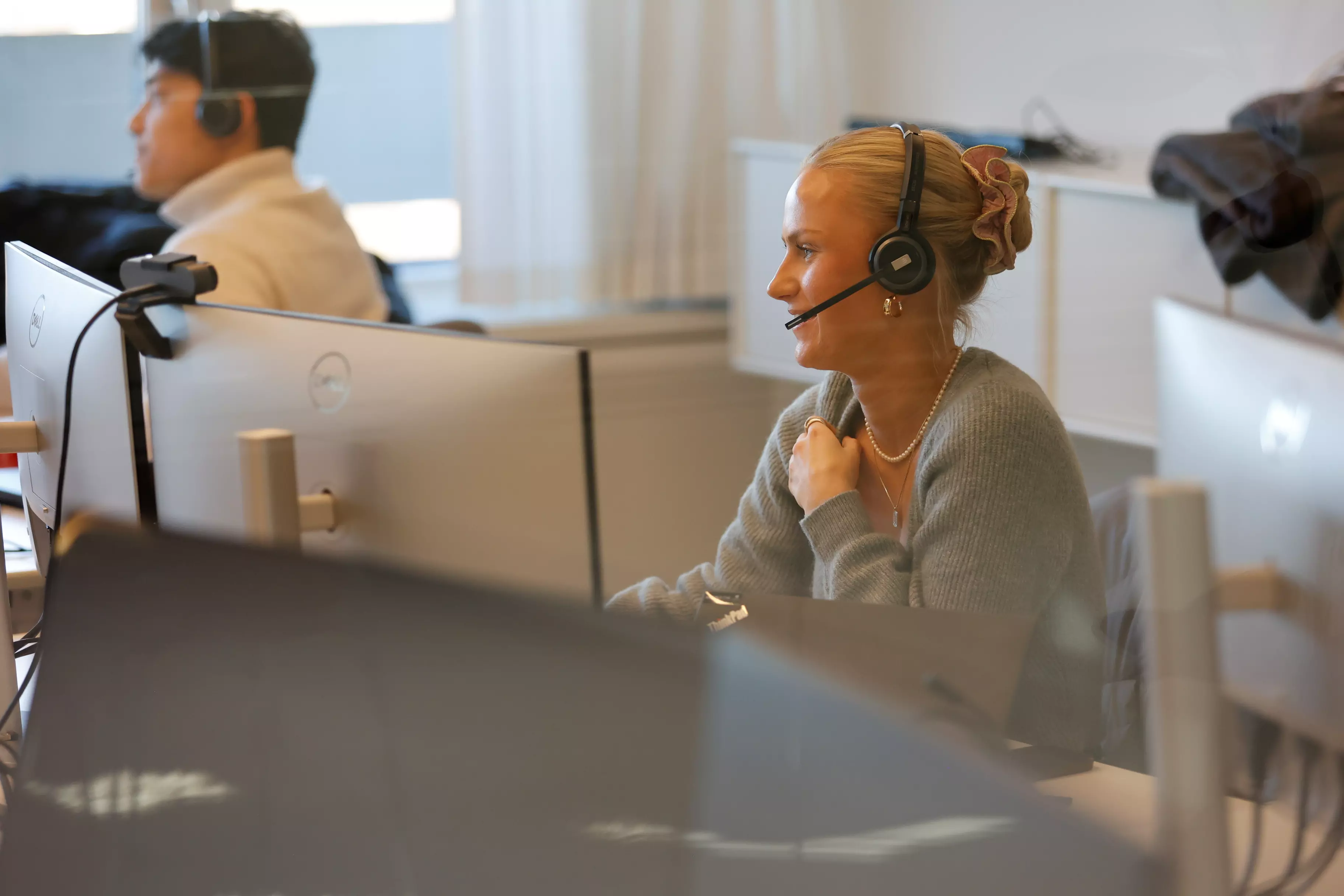 En mand og en kvinde sidder ved hver deres computerskærm og arbejder.