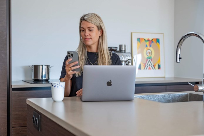 Kvinde med smartphone og computer. Forebyg identitetstyveri online.