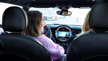 To kvinder i en bil med fokus på bilens instrumentbræt