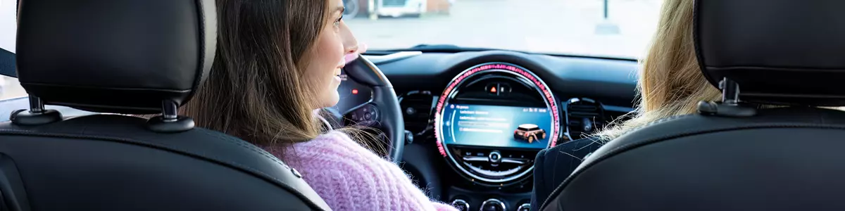 To kvinder i en bil med fokus på bilens instrumentbræt