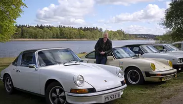 Billede af en klassisk bil og en mand der læner sig op af bilen og smiler.