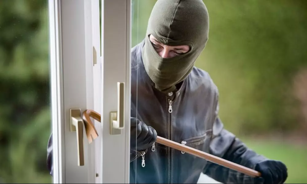 En tyv med elefanthue der er på vej til at brække en dør op.
