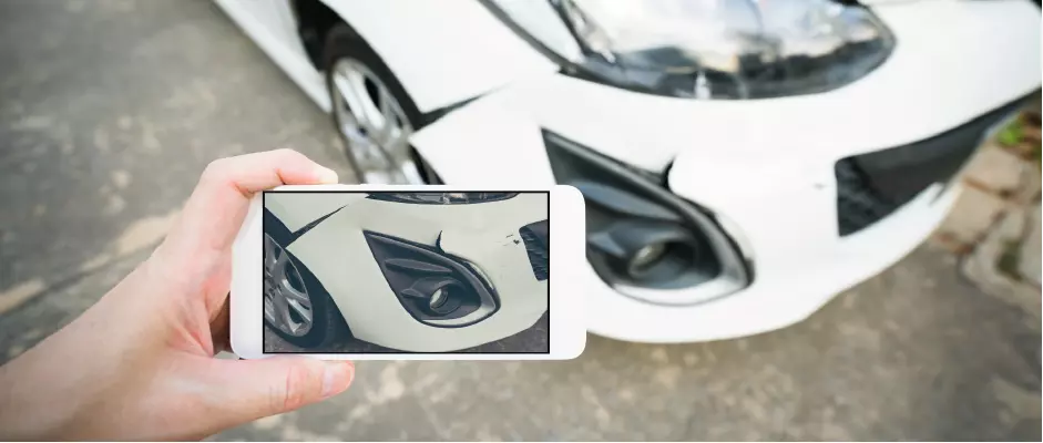 Billlede af en smartphone, der tager et billede af fronten på en bil med en skade.