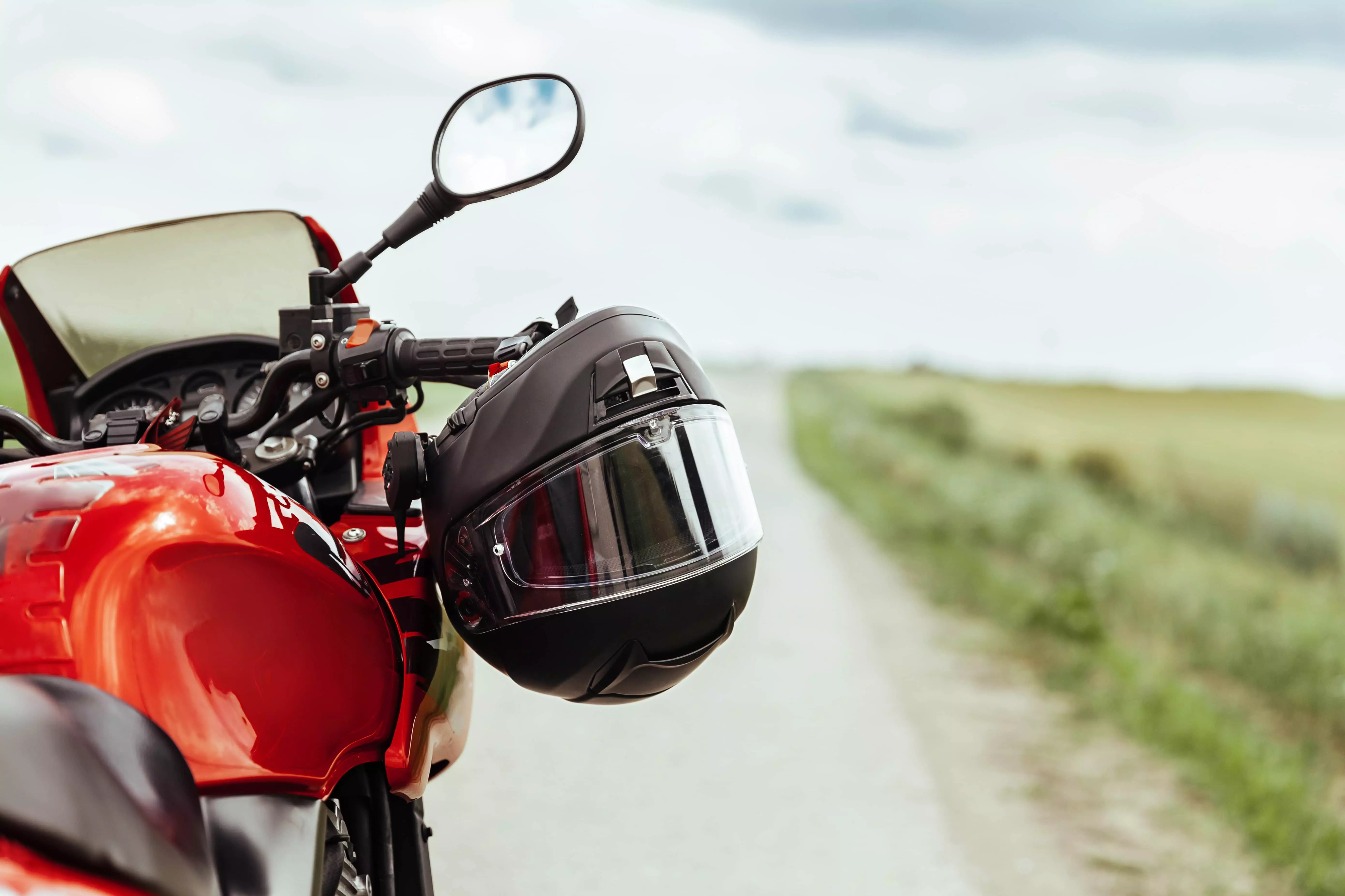 En motorcykel holder på en landevej og der hænger en hjelm på styret.