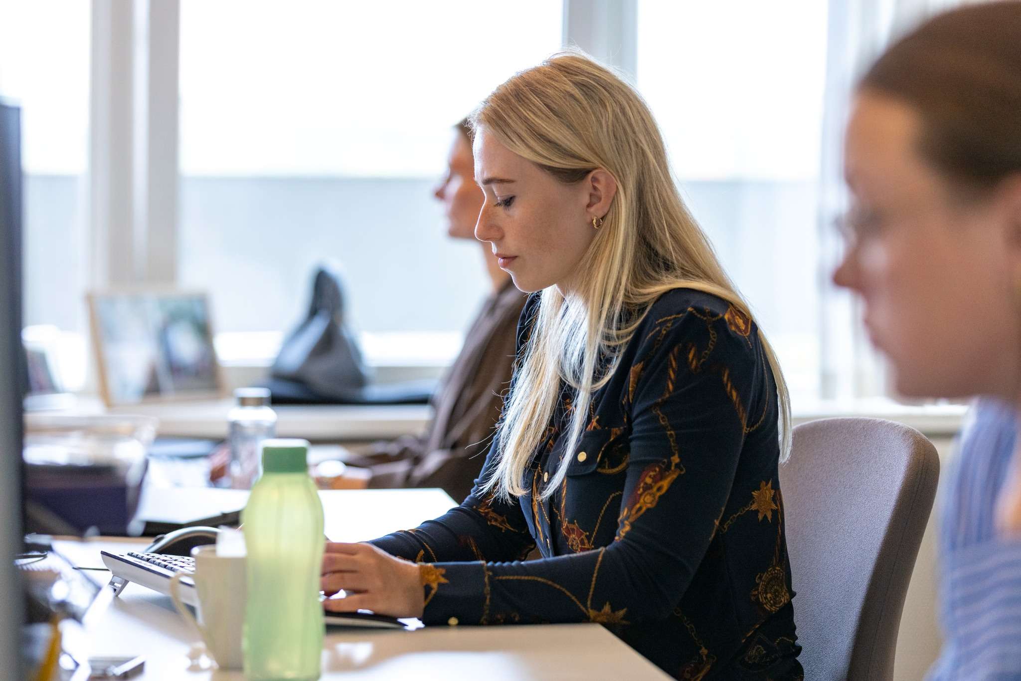 Medarbejder koncentreret foran tastatur i åbent kontormiljø