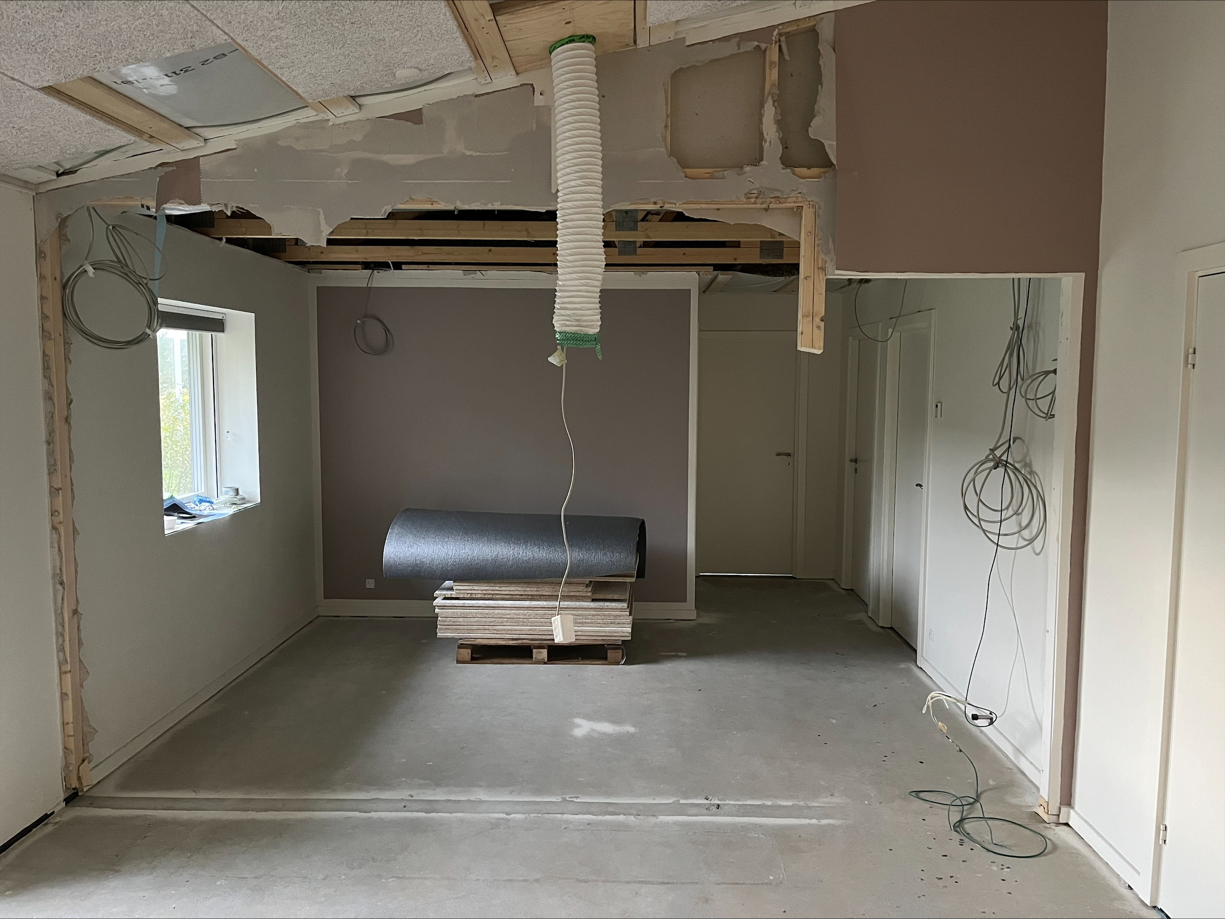 Råt lokale under renovering med blotlagt loft og kabler, klar til ombygning