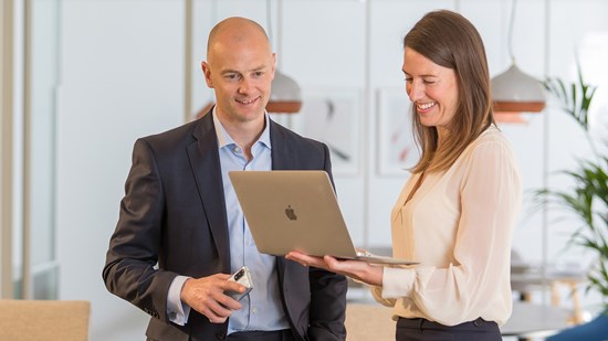 Colleagues smiling whilst looking at a laptop in the office