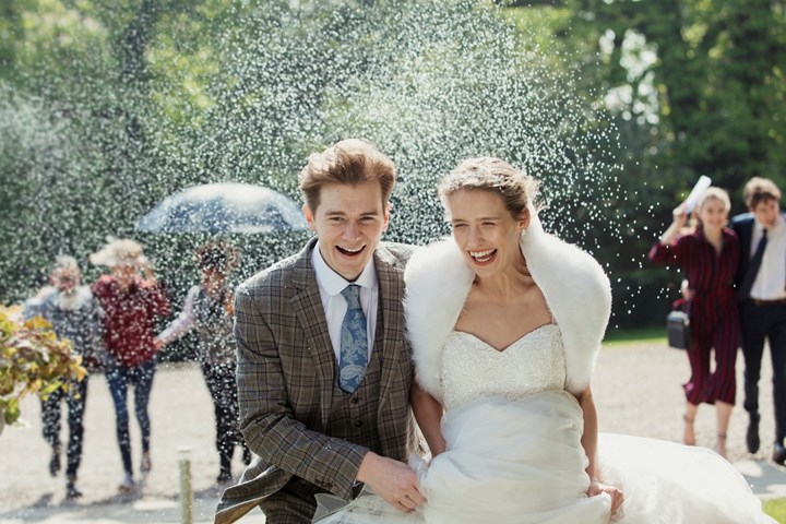 Bride and groom walking through confetti shower