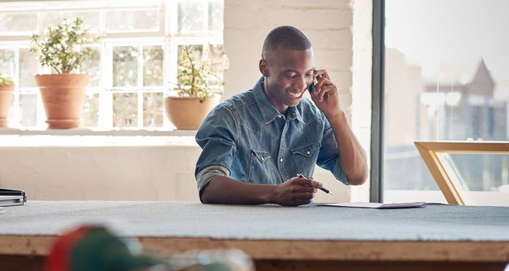 Person on phone sitting at desk smiling