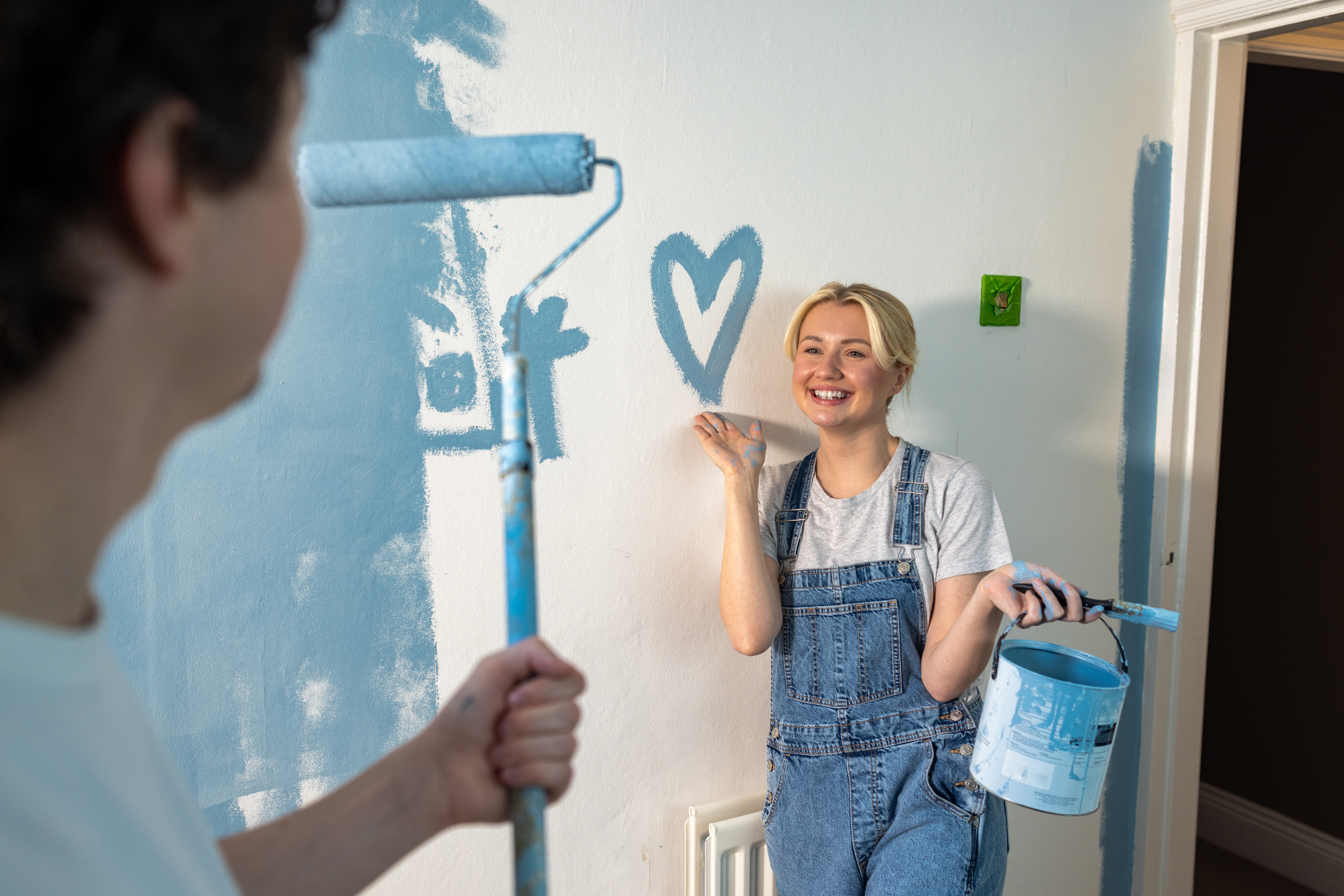 Smiley couple repainting their living room