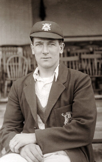 A black and white picture of Nottinghamshire cricketer Harold Larwood in a team blazer and cap.