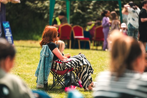 A woman and her child sitting on deckchairs surrounded by people at an outdoor event at Selston Country Park