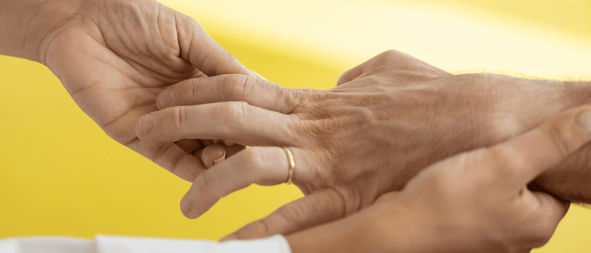 Uma mão de um paciente a ser avaliada por duas mãos de um médico