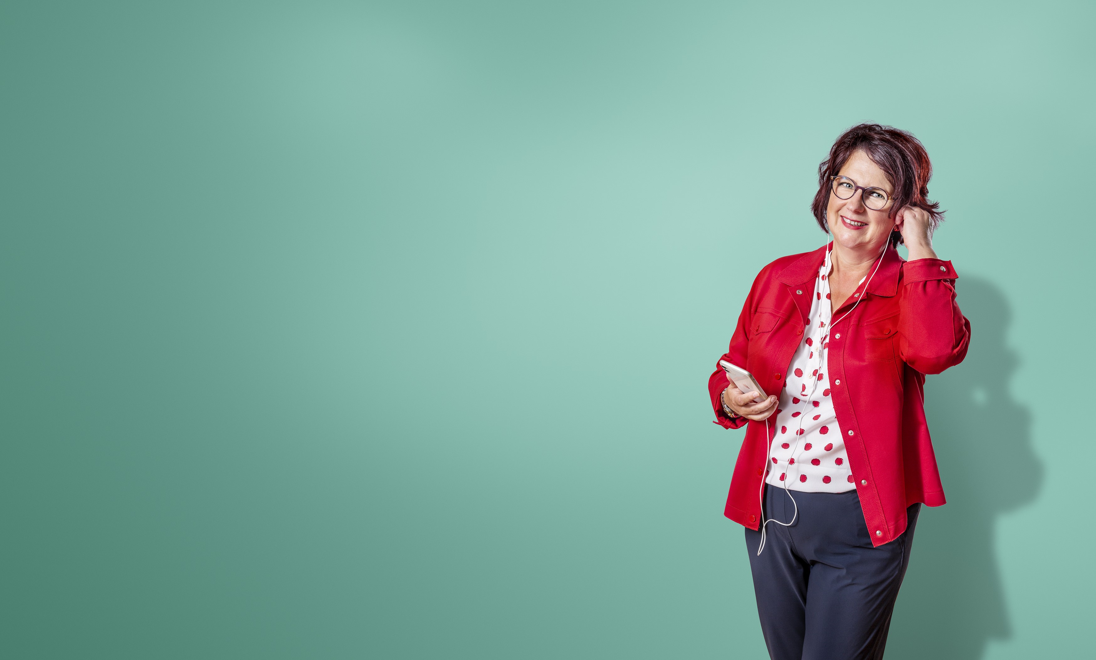 Vrouw met bril doet oordopjes van telefoon in.