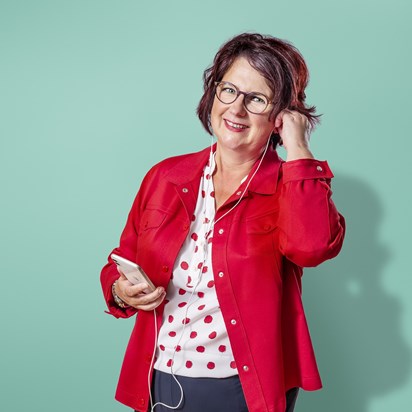 Vrouw met bril doet oordopjes van telefoon in.