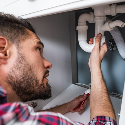 Loodgieter repareert sifon onder gootsteen