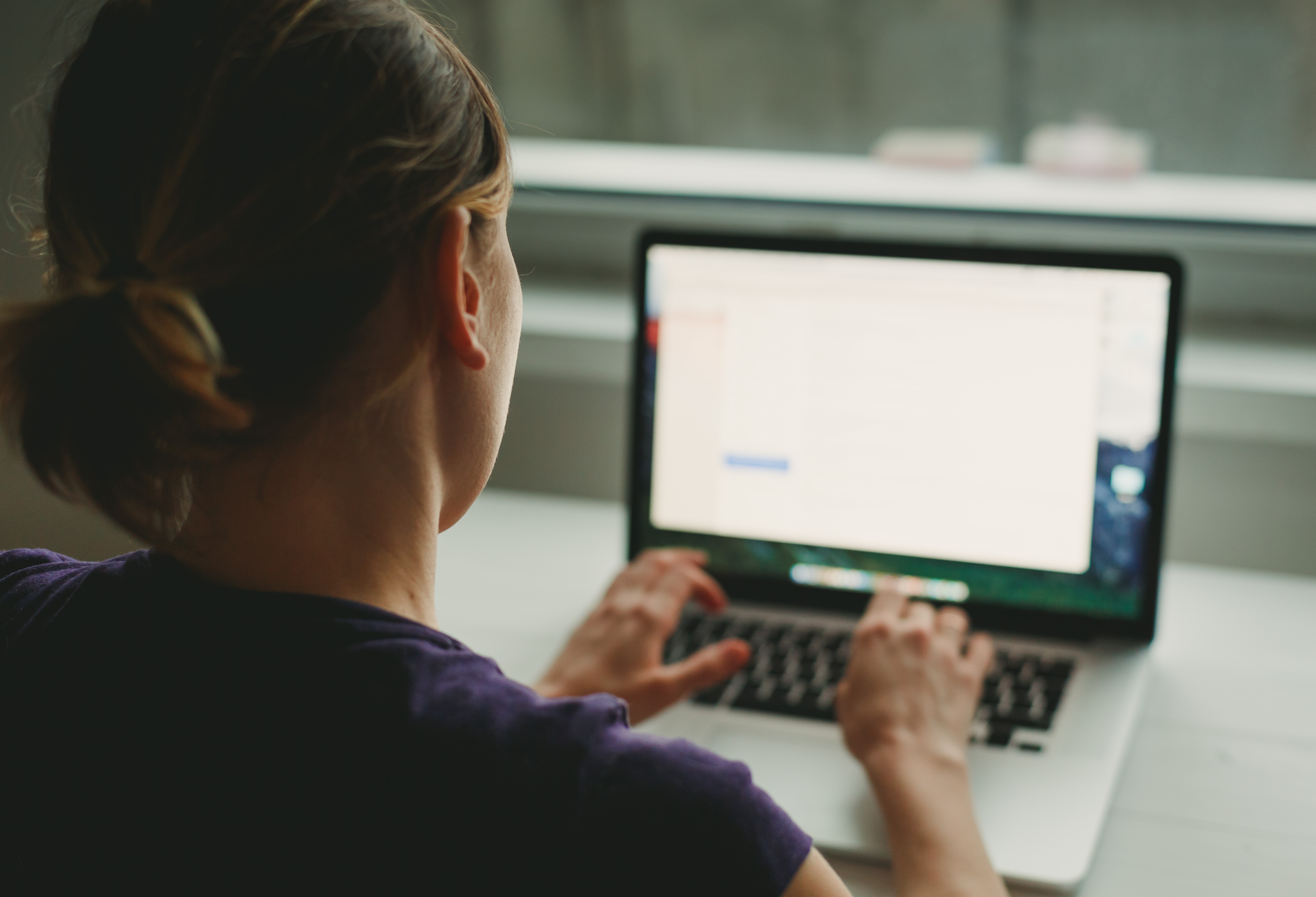 Vrouw vanaf rug bezien werkt op laptop