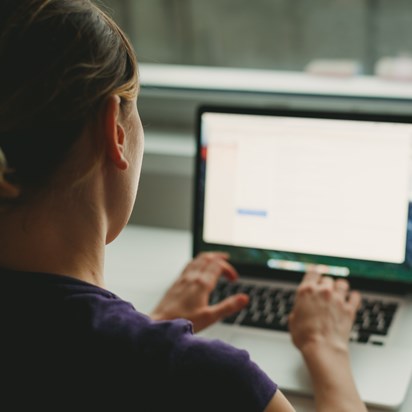 Vrouw vanaf rug bezien werkt op laptop