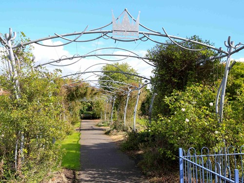 Metal archway with metal crown surrounded by trees at Kingsway Park