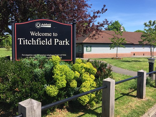 A Welcome to Titchfield Park sign behind some green bushes