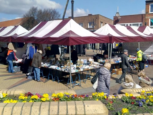 Customers at red and white striped market stalls at Sutton Outdoor Market