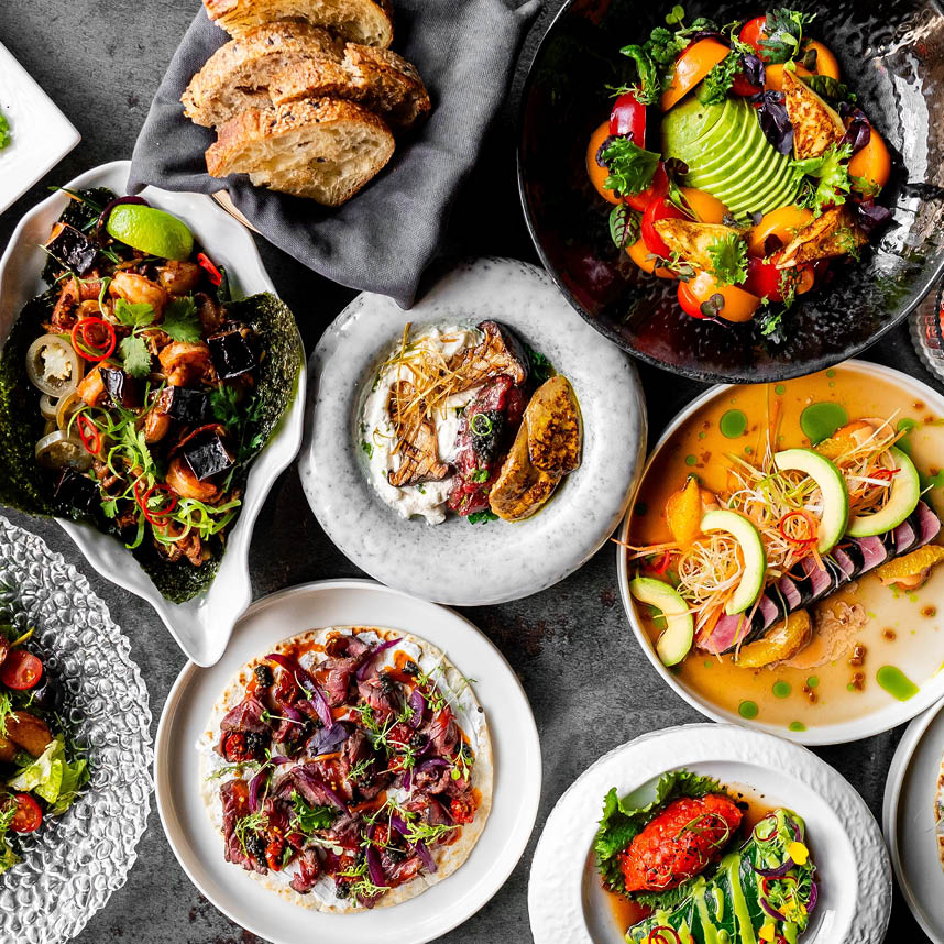 Top view of a variety of gourmet dishes, including salads, meat, seafood, and fresh bread.