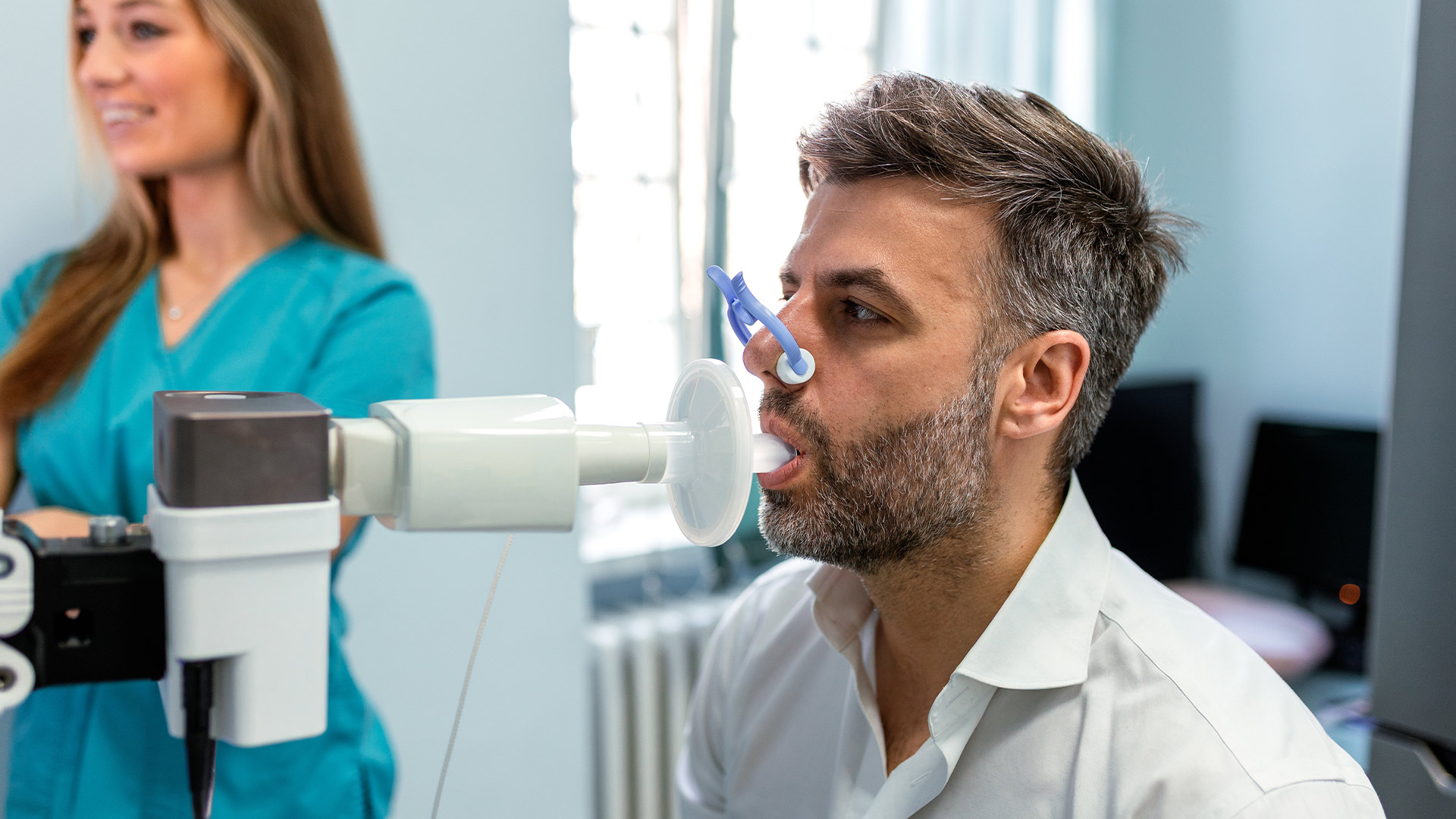 profissional de saúde a realizar o exame de espirometria a um paciente