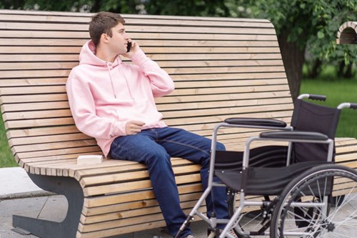 A guy with pink hoodie sitting on a public place and talking to phone