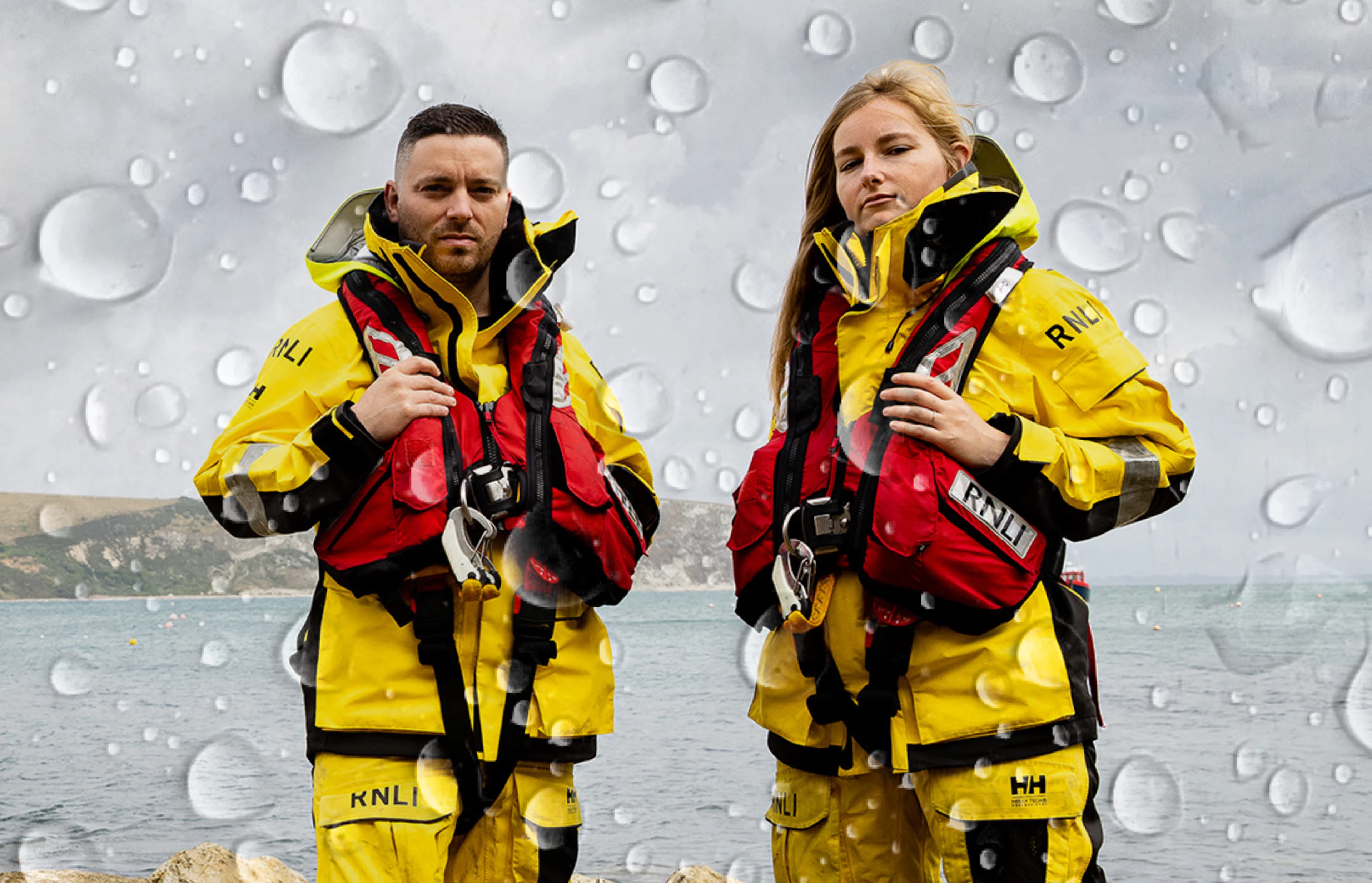 Image of two RNLI crew in front of the sea