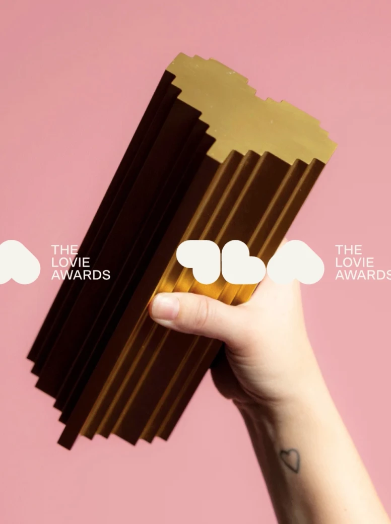 A hand holding a Lovies award with lovie awards wording in front of it