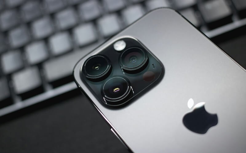 Close up of grey iPhone Pro model with triple camera setup.