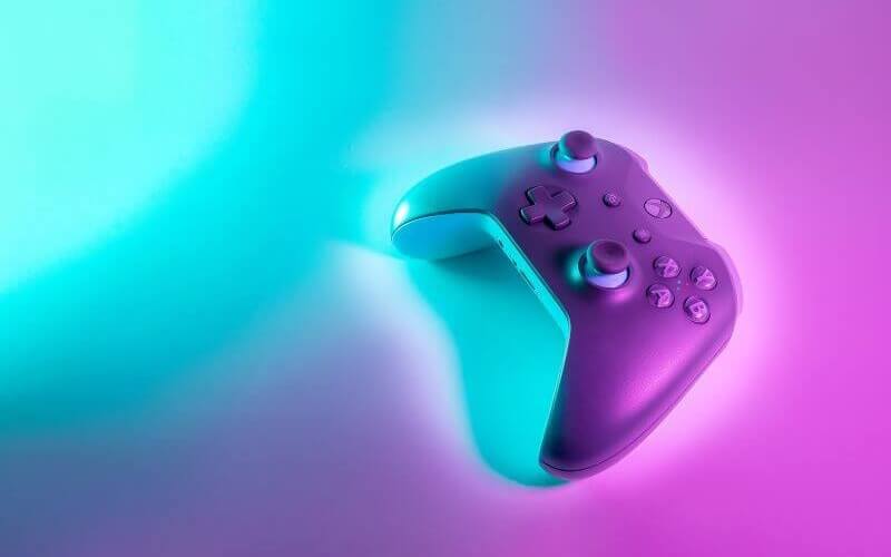 A black Xbox One controller with a blue and purple cash of light shining over it