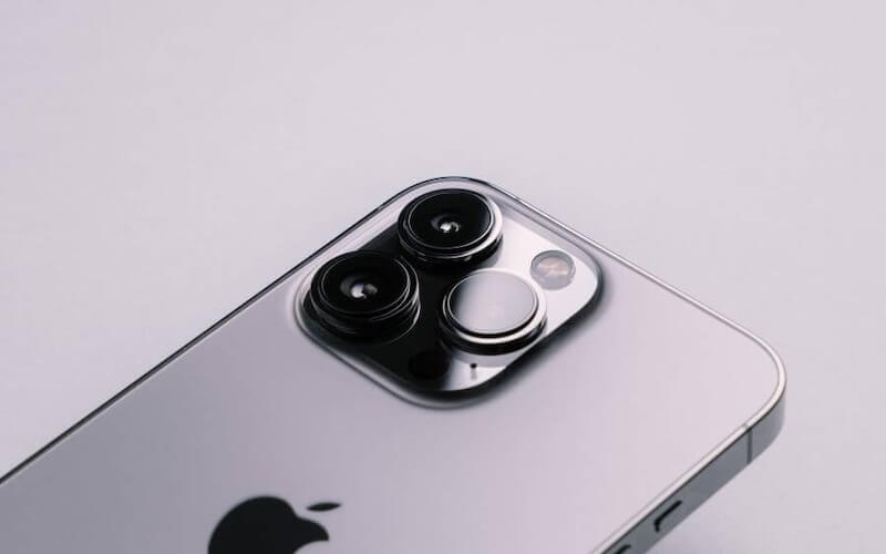 A close up of a grey iPhone 13, focusing on the triple camera layout on the back of the device.