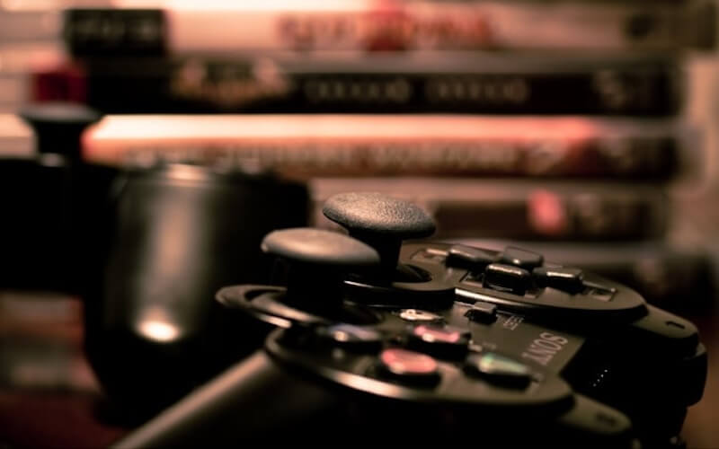 A PS3 controller with a tower of PS3 games in the background.